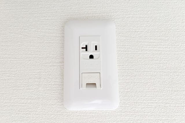 白い壁に取り付けられた電源コンセント
